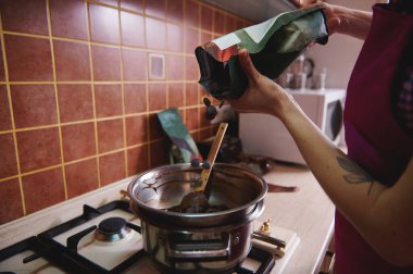 Erimiş çikolatayı ısıtmak ve pişirmek için çikolata tabletlerini su banyosuna atan pasta şefi ya da çikolata üreticisinin kırpılmış görüntüsü. Yakın çekim.