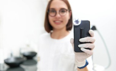 Doktorun elindeki benleri, deri gelişimlerini ve neoplazmaları analiz etmek ve incelemek için bir dermatoskoba odaklanın. Erken kanser tespit kavramı