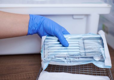 Çelik diş aletlerini yükleyen dişçi sterilizasyon için buharlı otoklavda hava geçirmez ambalaja kapatıldı.