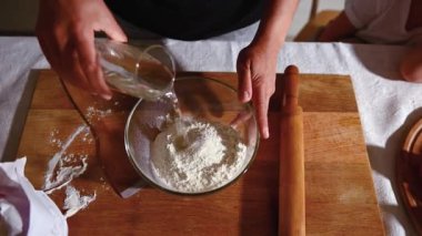 Yakın plan kadın hamuru yoğurmak için şeffaf bir kâseye un döküyor. Mutfakta hamur yapmanın kısa video materyalleri. Yavaş çekim