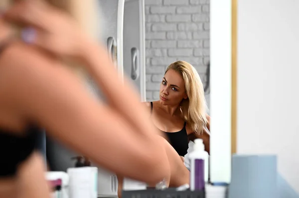 Young Beautiful Woman Straightens Her Hair Looking Herself Mirror — Foto de Stock