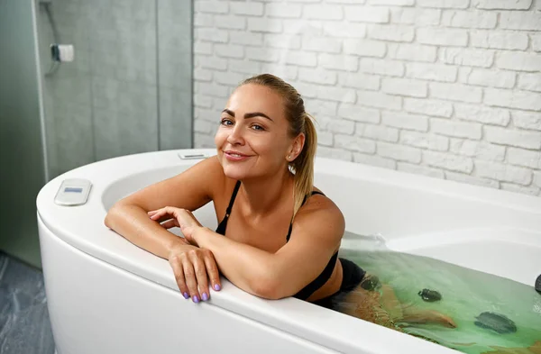 Glad Vacker Kvinna Ler Mot Kameran Medan Njuter Hydromassage Och — Stockfoto