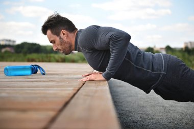 Handsome middle aged sportsman goes in for outdoor sports, push ups on the playground. Concepts of active and healthy lifestyle,outdoor workout