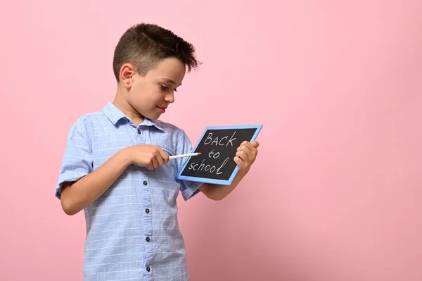 幸せな生徒の手にチョークボード上の学校に戻る手紙 ピンクの背景にコピースペースで隔離されています — ストック写真