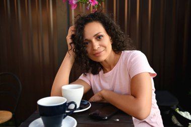 Afro-Amerikan güzel bir kadının portresi masaya oturmuş, kafeteryada kahve molası veriyor.