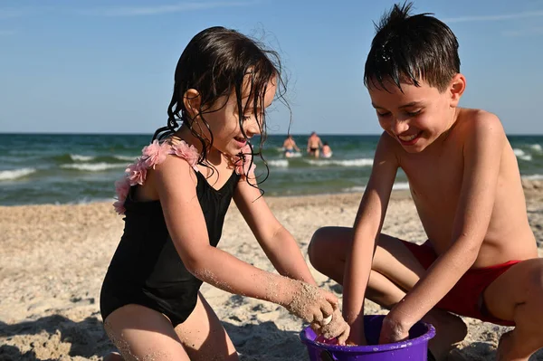 Szczęśliwy Brat Siostra Przyjaciele Chłopiec Dziewczyna Wypełniając Fioletowe Plastikowe Wiadro — Zdjęcie stockowe