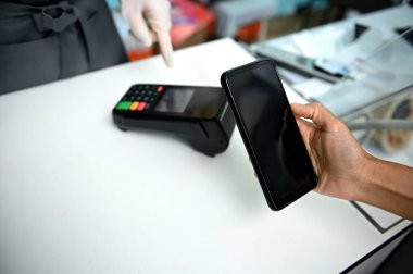 Deniz ürünleri dükkanında akıllı telefonu olan bir müşteri. Temassız ödeme konsepti. Bir deniz ürünleri dükkanında NFC teknolojisini kullanarak faturayı akıllı telefondan ödemek. Müşteri memnuniyeti cep telefonuyla iletişim teknolojisi kullanarak ödeme yapıyor..