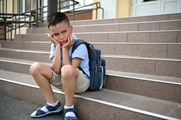 いじめ 勉強の難しさ 心配している男の子を動揺させ バックパックを学校で階段に座って — ストック写真