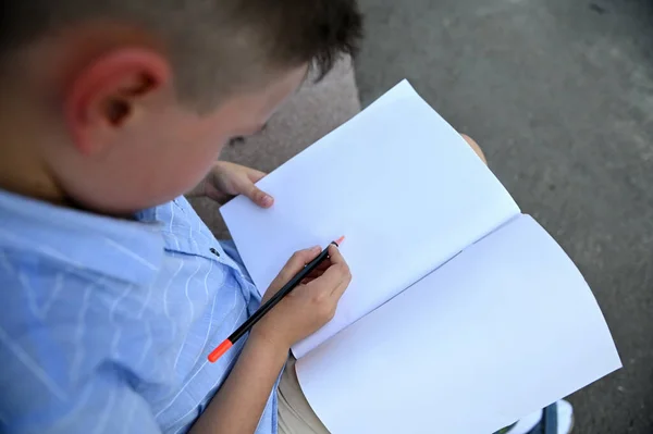 ワークブックの白い空白のペーパーシートに書いている学校の少年のオーバーヘッドビュー コピースペース 学校に戻る トップ表示 — ストック写真