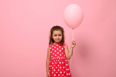 Çok güzel, tapılası bir güzelliğin portresi 4 yaş doğum günü kızı, benekli bir çocuk, pembe bir balon tutuyor, pembe arka planda reklam için izole edilmiş..