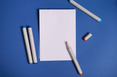 Dichromatic düz bileşimi ile suluboya işaretleyiciler veya keçeli kalemler ile fotokopi alanı ile beyaz boş kağıt sayfa, mavi arkaplan izole.