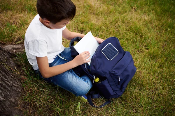 Vista Aérea Niño Edad Preadolescente Sacando Cuaderno Ejercicios Mochila Sentado —  Fotos de Stock