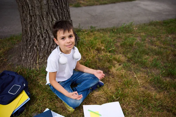 Stilig Elementär Åldrad Skolpojke Sitter Lotusställning Det Gröna Gräset Offentlig — Stockfoto