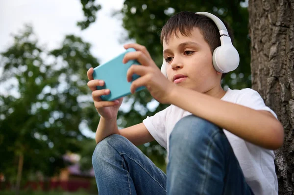 Adorable Colegial Primaria Con Auriculares Inalámbricos Jugando Con Teléfono Móvil —  Fotos de Stock