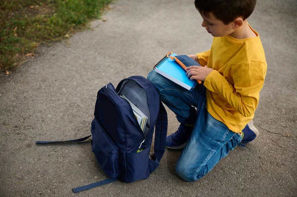 Charmig Elementär Åldrad Skolpojke Sitter Knä Stig Parken Sätter Anteckningsbok — Stockfoto