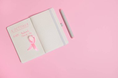 Pembe kurdele, üzerinde tıbbi muayeneyi hatırlatan yazıtlar var. 1 Ekim, Dünya Göğüs Kanseri Günü, Kadın Sağlığı Konsepti. Pembe gün, Dünya Kanser Günü, Ulusal Kanser Kurtulan Söyle.