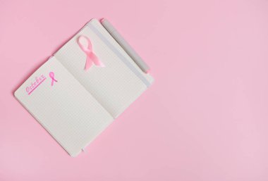 1 Ekim 'i bir günlüğe ve boş bir kâğıt üzerinde pembe bir kurdeleye kopyalama alanı olan pembe arka planda izole edilmiş. Ekim Pembe Günü, Dünya Kanser Günü, Ulusal Kanser Kurtulan Söyle.