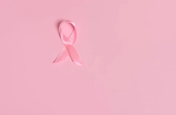 Flat lay of a satin pink ribbon awareness, International symbol of Breast Cancer Awareness Month in October. Isolated over on pink background with copy space . Women\'s health care and medical concept.