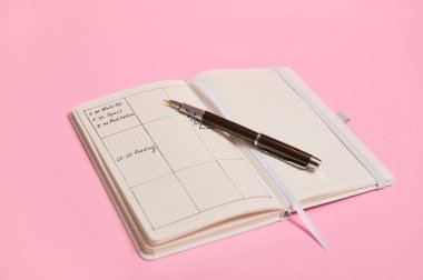 İş günlüğü, ofis organizatörü planları. Pembe arkaplan, kopyalama alanı. Planlayıcı şablonları ve günün çizelgesi günlükte işaretlenen saatlere ve açık bir defterde duran mürekkep kalemiyle