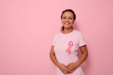 Uluslararası Göğüs Kanseri Gününü sembolize eden pembe saten kurdeleli pembe tişörtlü, gülümseyen bir ırk kadını göğüs kanseri hastaları ve hayatta kalanlara destek ve dayanışma gösteriyor. 1 Ekim