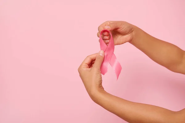 Woman\'s hands holding a pink ribbon, symbol of World Breast Cancer awareness Day, in 1 st October. Woman\'s health and medical concept, October Pink day, World Cancer Day, national Cancer Survivor Day.