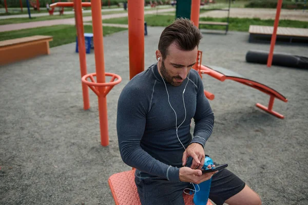 Όμορφος Καυκάσιος Αθλητής Που Φοράει Ακουστικά Κρατάει Ένα Smartphone Και — Φωτογραφία Αρχείου