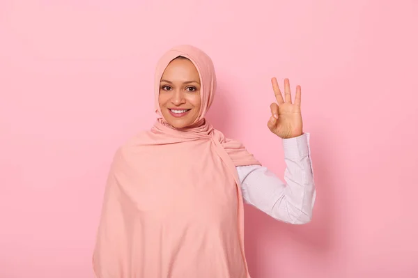 魅力的な喜び若いアラブのイスラム教徒のかわいい女性は 伝統的な宗教衣装を身に着けているとコピースペースとピンクの背景に立って カメラを見て Okサインを示すヒジャーブで頭をカバー — ストック写真