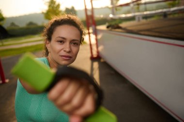 Sabahın erken saatlerinde spor yapan çekici bir sporcu, spor sahasında boks yapmak için halterleri kullanan bir kardiyo antrenmanı yapıyor.