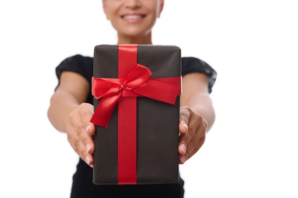 一个黑色礼品盒的特写 手上拿着红丝带 手上拿着一个笑容可亲的女人 穿着黑色的衣服 背景白色 有复制的空间 周年纪念日 黑色星期五及庆祝概念 — 图库照片