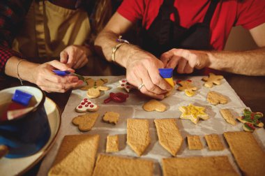 İnsanların parşömen üzerinde kurabiye kestikleri, renkli kesiciler ve şekiller kullandıkları, birlikteliği, tatil ruhunu ve paylaşılan tarifleri kutladıkları sıcak, ortak bir yemek sahnesi..