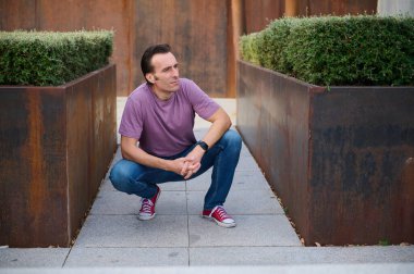 Sıradan bir adam, geniş paslı tarlalar arasında, şehir dışında bir yerde, mor bir gömlek, kot pantolon ve kırmızı spor ayakkabı giyerek, rahat bir spor, sokak tarzı, ve düşünceli bir ruh hali içinde,.