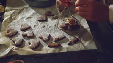 Eller dikkatlice kurutulmuş portakallarla süslenmiş ve sicimle bağlanmış aromatik zencefilli kurabiye yığınını hazırlar. Yürek ısıtan bir Noel hediyesi için mükemmel..