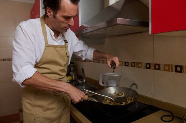 Bej önlüklü bir adam ocakta yemek pişirir, mantarlı bir tavaya sıvı döker. Sahne ev yemeklerini, aile hayatını ve akşam yemeği hazırlıklarını çekiyor..