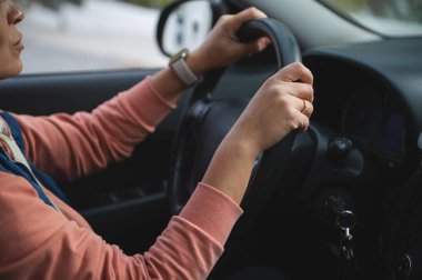 Direksiyona sıkıca sarılan bir sürücünün yakın plan fotoğrafı. Odaklanma, güvenlik ve günlük yolculuk. Yolculuk, yol gezisi ya da aile seyahatleri için ideal..