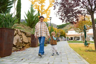 Bir anne ve yeni yürümeye başlayan bir çocuk güneş ışığıyla aydınlatılmış bir sonbahar parkında yürüyor, yaprakları dökülürken el ele tutuşuyorlar. Sıcak, şefkatli bir an aile sevgisini ve tasasız çocukluğunu yakalıyor..