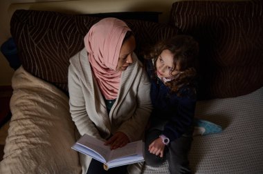Pembe başörtüsü takan Müslüman bir anne genç kızıyla rahat bir kanepede kitap okuyup kitap paylaşır. Sıcak, samimi bir aile bağı ve günlük yaşam..