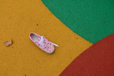 Çiçek desenli tek bir pembe spor ayakkabı canlı sarı, yeşil ve kırmızı kaldırıma dayanır ve oyuncu bir sokak tarzı anı yaratır. Gençlik modası, yaz yaşam tarzı ve stok çekimleri için harika..