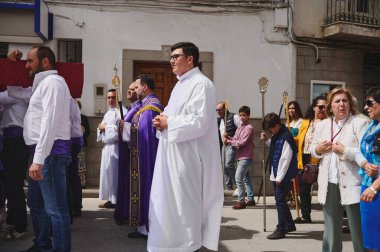 Quesada, Endülüs, İspanya. 18 Nisan 2024. Beyaz cüppeli ve parlak mor cüppeli rahiplerle dolu bir sokak dini geçidi. Güneşli bir günde etrafları aileler ve seyircilerle çevrili..
