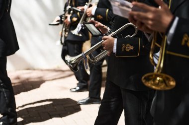 Quesada, Endülüs, İspanya. 18 Nisan 2024. Resmi üniformalı müzisyenler trombon ve trombon çalarlar. Güneşli bir etkinlikte sokak performansı için prova yaparlar..