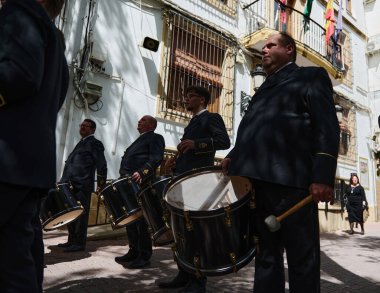 Pirinç davullar, Endülüs caddesinde resmi giyinmiş müzisyenlerin sıkı bir şekilde yürüdüğü gibi yürür. Quesada, Endülüs, İspanya. 18 Nisan 2024. Düzenleyici kullanımı.