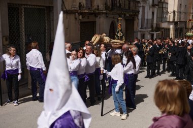 Büyük bir grubun yürüdüğü, bir heykel taşıdığı bir tören sokak geçidi ve onu takip eden bir bando. Topluluk, gelenek ve şenlik kıyafetleri Endülüs kültürünü yansıtır. Quesada, Endülüs, İspanya. 18 Nisan 2024