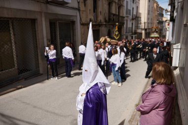Quesada, Endülüs, İspanya. 18 Nisan 2024. Dar bir sokakta dini bir geçit töreni. Kapüşonlu katılımcılar ve izleyiciler gelenekleri ve toplumu esir alıyor..