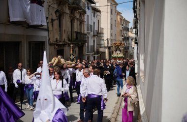 İspanya, Endülüs 'te, Quesada' da beyaz gömlekli ve mor kuşaklı yerliler heykel taşıyor. Bu editoryal olay sırasında izleyiciler dar şeritler çiziyor. Quesada, Endülüs, İspanya. 18 Nisan 2024