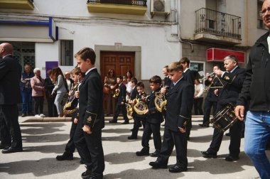 Quesada, Endülüs, İspanya. 18 Nisan 2024. Editör kullanımı. Resmi üniformalı gençlerle halka açık bir geçit töreni. Seyirciler güneşli bir caddede sıraya dizilirken pirinç oyunu oynuyorlar..