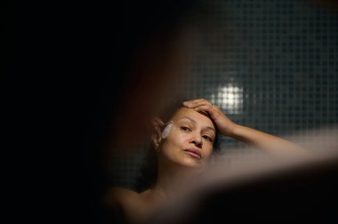 40 'lı yaşlarda genç bir kadının Gua-Sha masözüyle yüzüne masaj yaptığını hayal et. Yaşlılara karşı güzellik spa tedavisi.