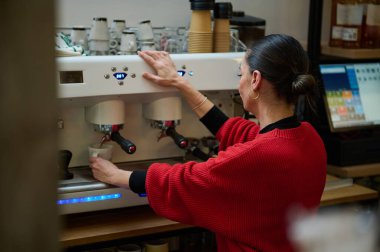 İspanyol bir kafe sahibi, rahat bir kafede kahve hazırlayan profesyonel bir espresso makinesi kullanıyor. Konukseverliği, küçük işletmeleri ve günlük kahve hizmetlerini vurgular.