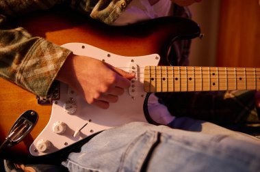 Bir gitaristin ellerinin elektro gitar ile yakın plan çekimi, fretwork, teller, ve sıcak ahşap kaplama.