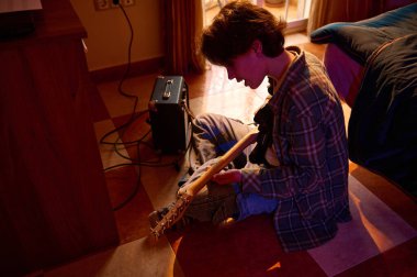 Genç bir gitarist sıcak, loş bir odada, küçük bir amplifikatörün yanında elektro gitarı akort ediyor veya ayarlıyor. Sahne, pratik, yaratıcılık ve rahat müzik yapma üzerine kurulu..