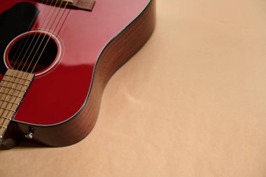 Telleri ve fretboard 'u gösteren, gitar bakımını gösteren, tamir ve bakım için telleri ayarlayan ve değiştiren kırmızı akustik gitarın yakın plan görüntüsü.