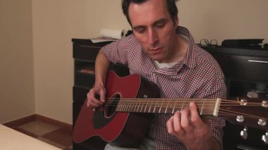 Kendini adamış bir sanatçı ve müzisyen titizlikle akustik gitarını çalar. Bu sahne müzik tutkusunu, enstrüman bakımını ve ustaca performansını temsil eder..